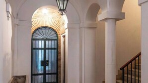 A hallway with a wooden floor, white walls, and a black gate at the end. - Navona Apartment (Rome)