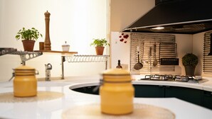 A kitchen with a white countertop, a stove, and various utensils hanging on a rack. - Navona Apartment (Rome)