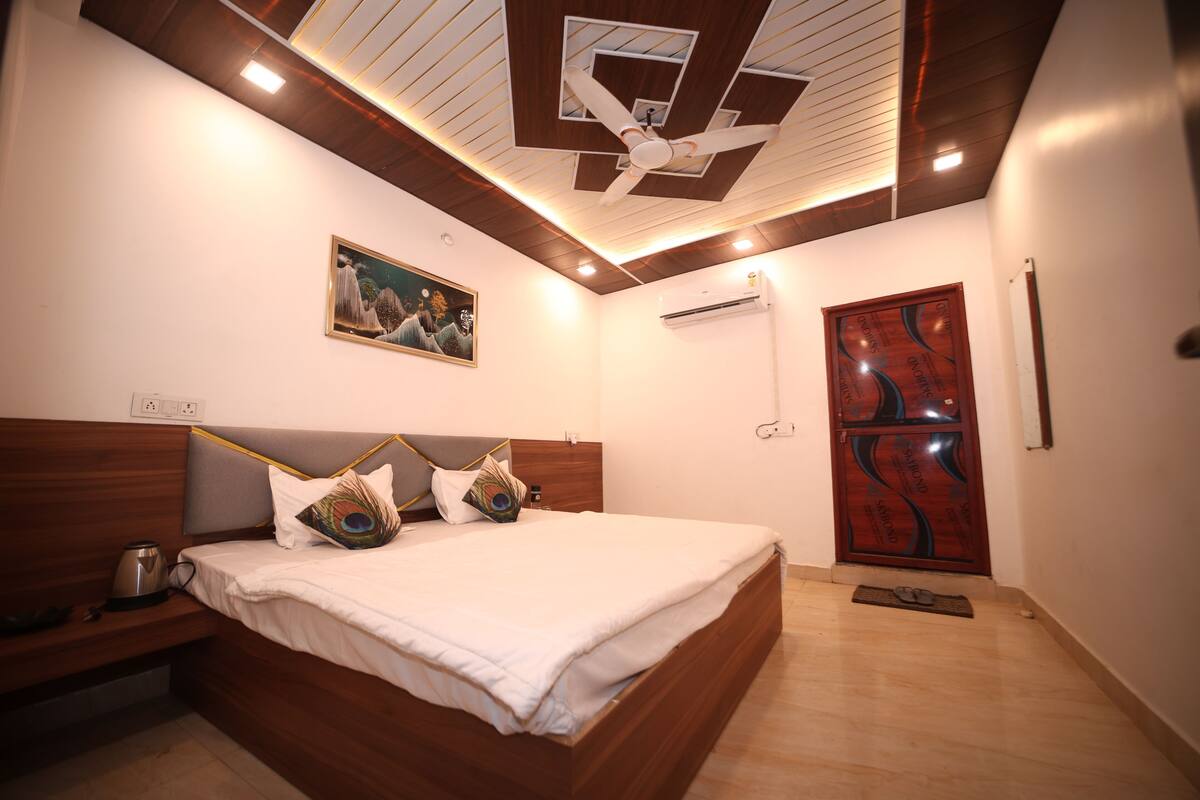 Een slaapkamer met een houten bed, een nachtkastje, een plafondventilator en een deur met decoratief ontwerp.