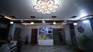 Un espace d’accueil doté d’un sol en marbre, d’un comptoir de réception, d’un plafond orné d’un luminaire circulaire et d’un écran de télévision fixé au mur.