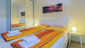 A hotel room with a bed, a bedside table with a lamp, a mirror, and a painting on the wall. - Modern villa with pool, garden and sea view for 8 people in Istria (Galižana)