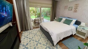 Camera da letto con un letto grande, una TV, una porta scorrevole in vetro su un patio e una luce a soffitto.