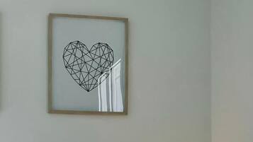 Una camera d'albergo con un letto, un comodino con una lampada e un quadro geometrico appeso alla parete.