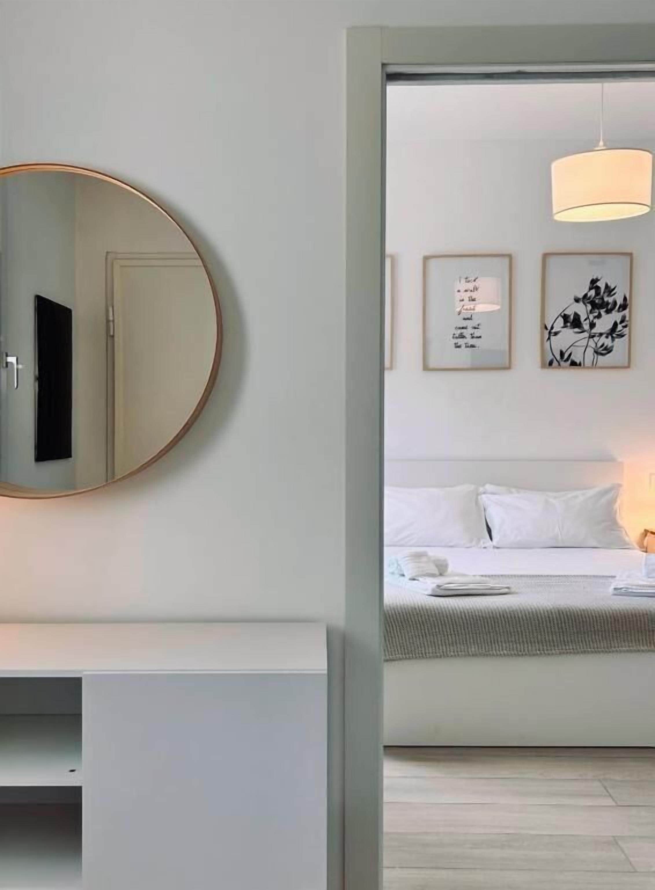 Quarto com uma cama, mesa de cabeceira, espelho e quadros na parede.