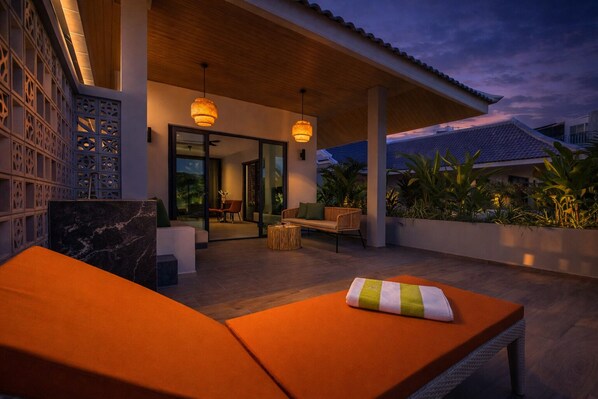Ein Außenbereich mit Lounge-Möbeln in Orange, Holzboden und hängenden Lampen.