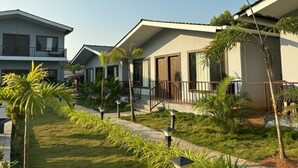 A row of modern buildings with balconies, surrounded by well-maintained lawns and palm trees.