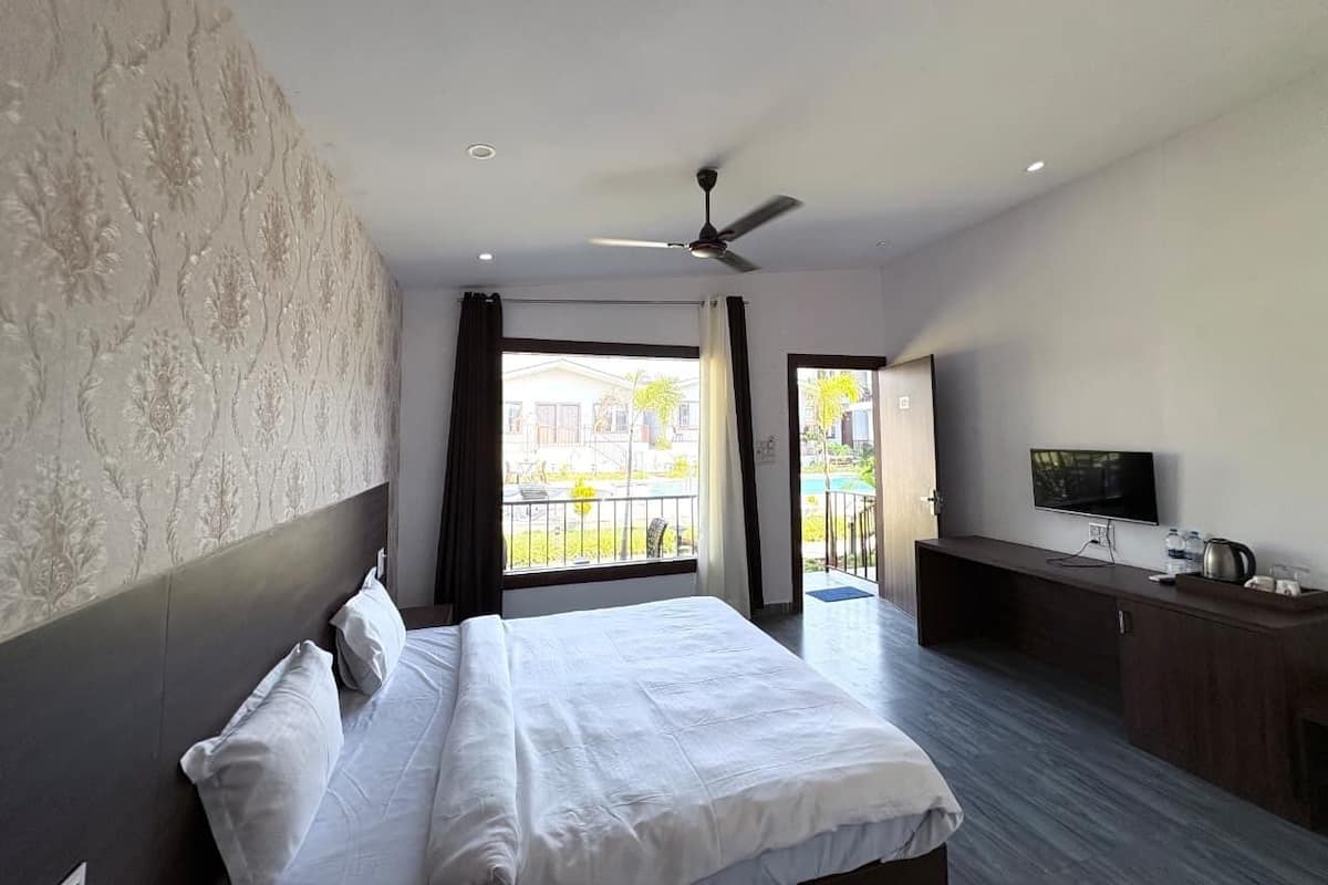 A hotel room with a bed, a TV, a desk, and a balcony with a view.