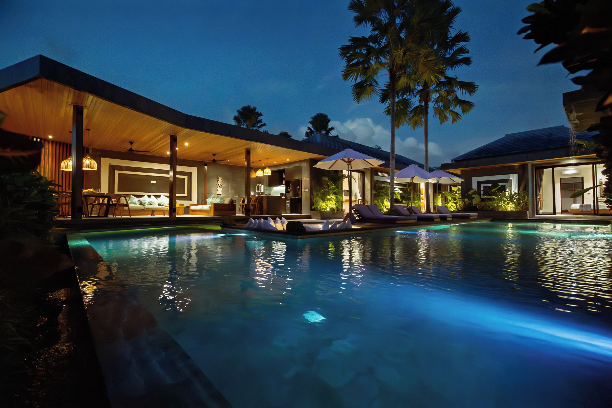 Un resort moderno con piscina, zona de estar y asientos cubiertos.