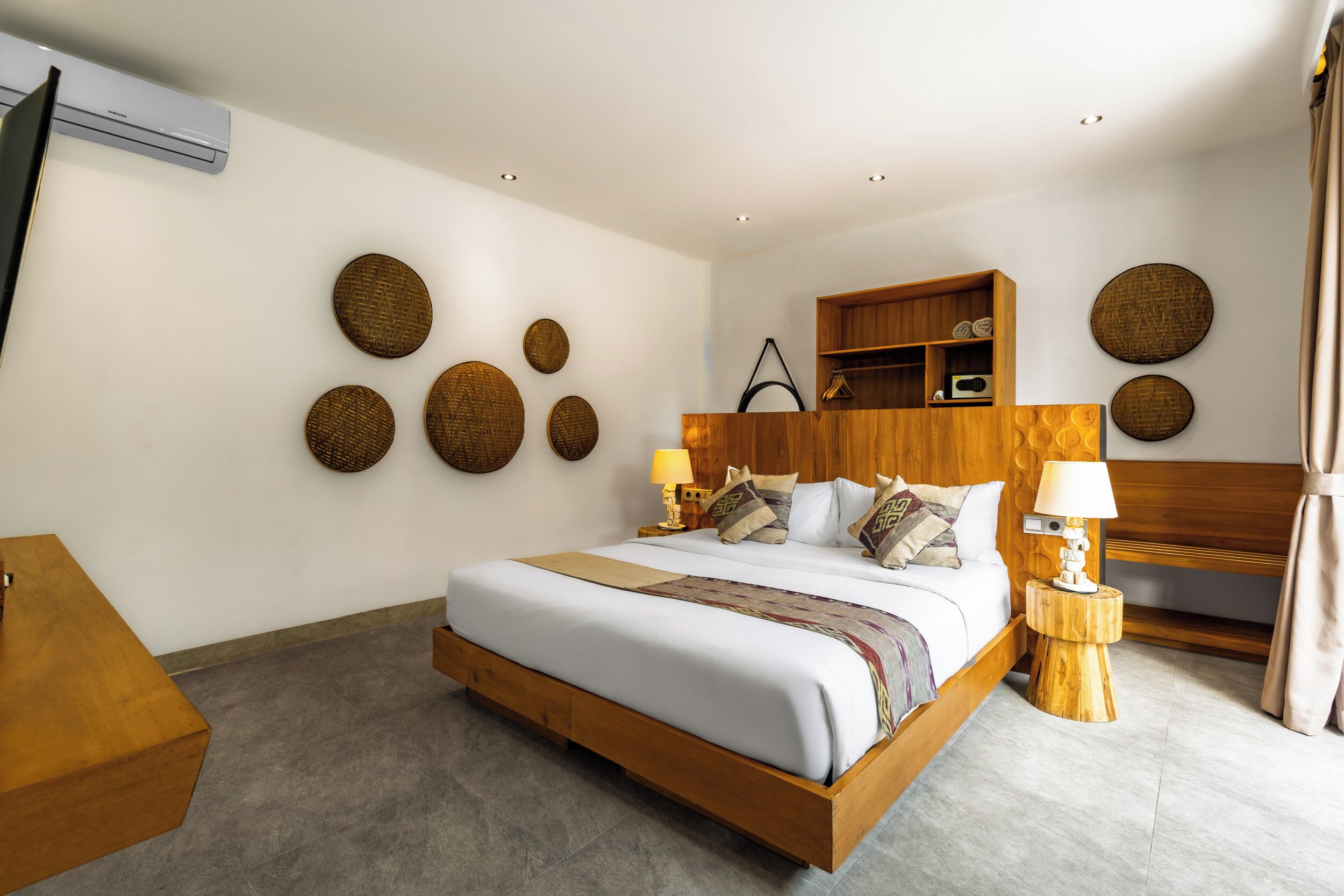 A modern bedroom with a wooden bed, a wooden nightstand, and a small wooden side table with a lamp.