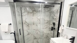 A modern bathroom with a glass-enclosed shower, a white sink, and a vanity with cabinets. - Delightful Studio in Montréal perfect for your city getaway (Montréal)
