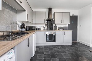 Ett modernt kök med diskmaskin, ugn och kaffemaskin.