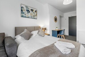 Ein Hotelzimmer mit einem Bett, einem Schreibtisch, einem Stuhl und einem Bild an der Wand.