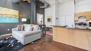 Un appartement moderne comprenant une cuisine, un espace de vie et un grand tableau accroché au mur.