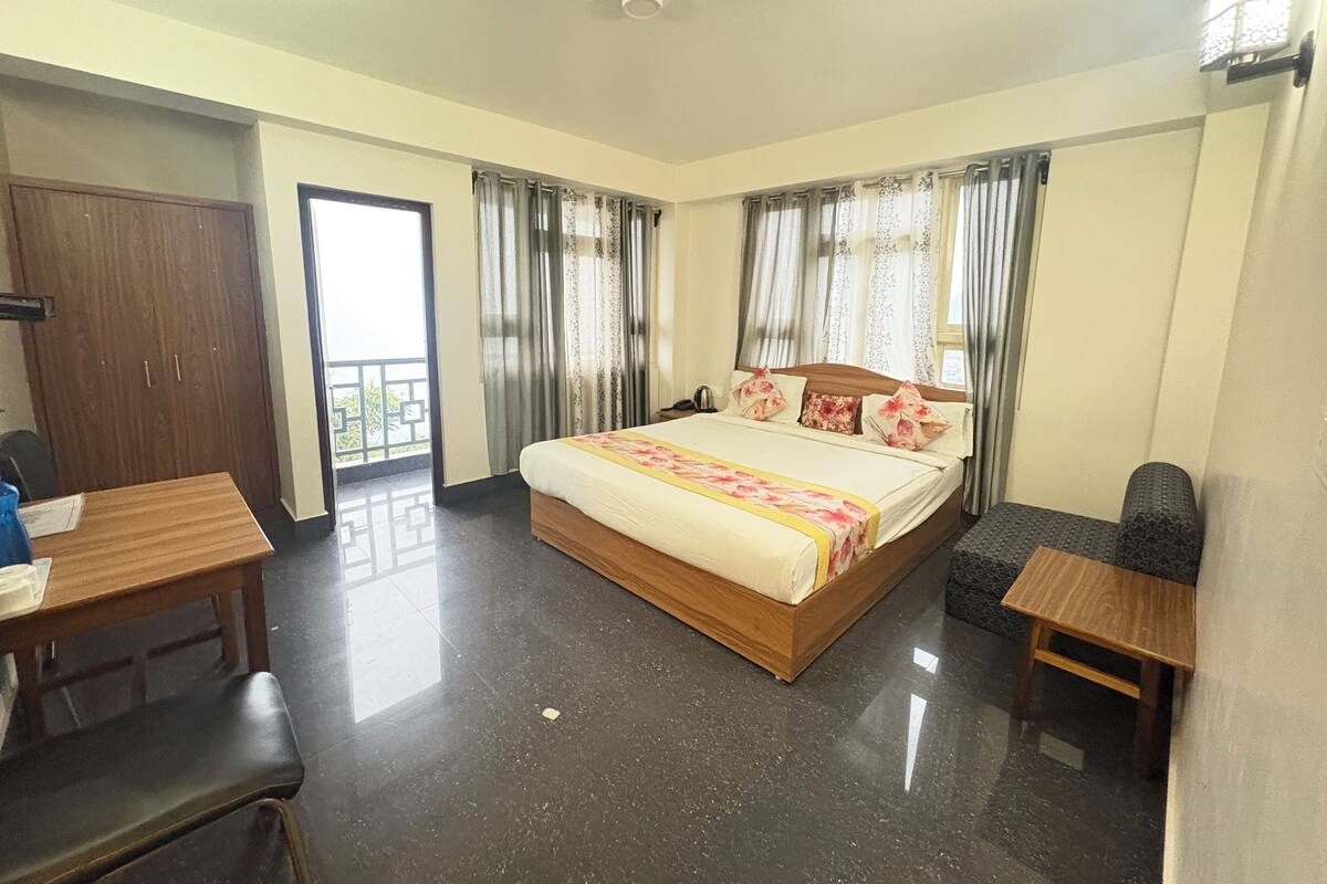 A hotel room with a bed, a desk, a chair, and a small table.