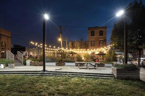An outdoor seating area with tables and chairs, surrounded by a low stone wall and a grassy area. - Live Artfully in This 2BR Stay (Philadelphia)