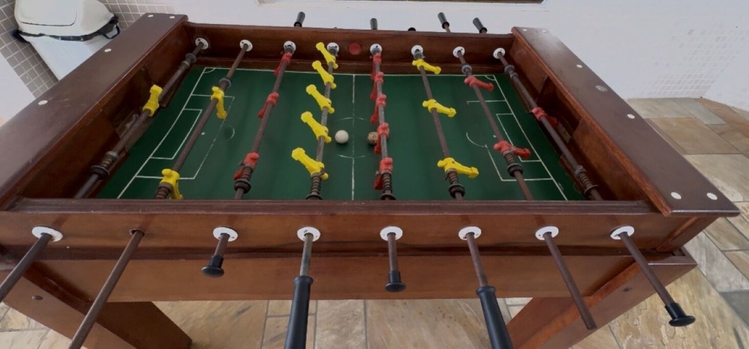 A foosball table with a wooden frame and multiple rods with red and yellow figures.