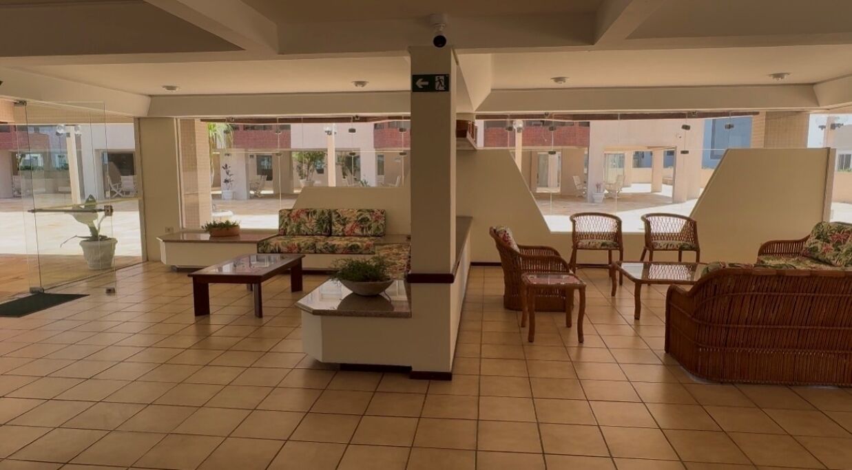 A spacious lobby with a high ceiling, tiled floor, and a seating area with wicker furniture.