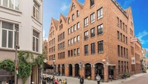 A multi-story brick building with arched windows and a corner entrance. - Apartment in Antwerp's Historic Center (Antwerpen)
