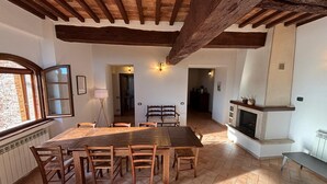 Un coin repas avec une grande table et des chaises en bois, une cheminée et une vue par la fenêtre.