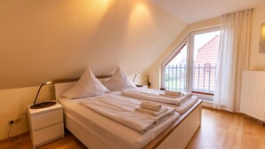 Une chambre à coucher avec un lit, une table de chevet, une lampe et une fenêtre avec des rideaux.