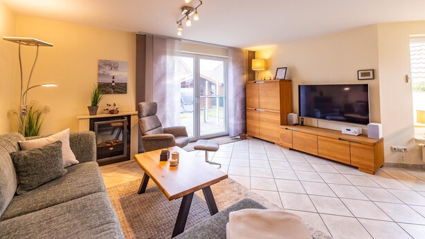 Un salon moderne comprenant un canapé, une table basse, une cheminée, un téléviseur et un meuble en bois.