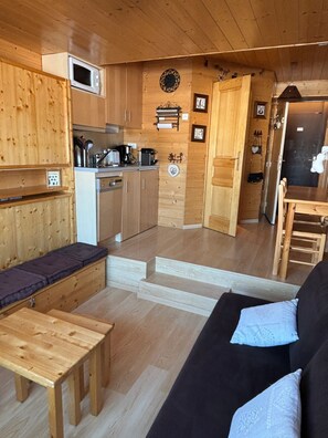 Interior acogedor de una cabaña de madera con kitchenette, comedor y sala de estar.