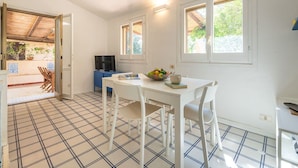 A kitchen with a tiled floor, a dining table with chairs, a blue cabinet, and a television. - Wonderful private villa for 4 guests (Villasimius)