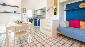 A modern apartment with a dining area, kitchenette, and a living room with a sofa and colorful cushions. - Wonderful private villa for 4 guests (Villasimius)