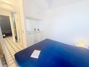Un dormitorio con cama, una mesita de noche, un espejo y un armario.