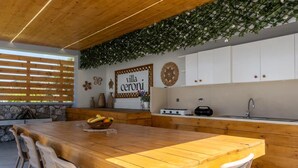 Eine moderne Küche mit Holztisch, weißen Schränken und einer Wand mit Pflanzenzierde.