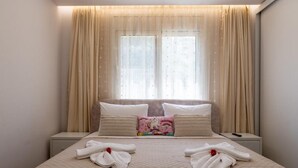 Ein ordentlich bezogenes Bett mit zwei Kissen, einem Zierkissen und zwei Handtüchern mit einem roten Blumenmuster.