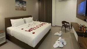 Een hotelkamer met een bed, een bureau, een stoel, een televisie en een airconditioning.