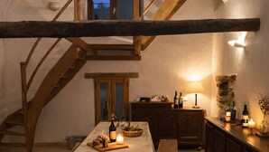 A cozy room with a wooden staircase, a dining table set with candles, and a sofa.
