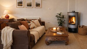 A cozy living room with a sofa, a coffee table, a fireplace, and framed pictures on the wall.