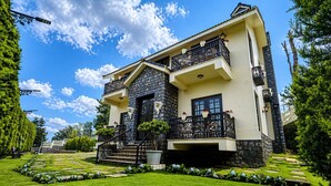 A two-story house with a stone facade, a balcony with decorative railings, and a well-maintained garden. - Lynton Resorts (Kotagiri)