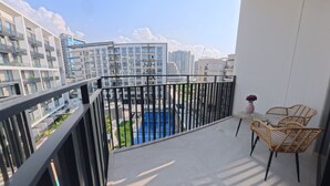 A balcony with a view of a swimming pool and surrounding buildings. - Beverly Boulevard By HMB HOMES (Dubai)