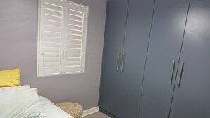 Un dormitorio con cama, armario y ventana con persianas.