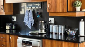 Una cocina moderna con armarios de madera, electrodomésticos de acero inoxidable y encimera negra.