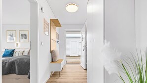 Un passadís amb un llit, una banca i una porta que condueix a una altra habitació.