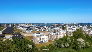 Zona residencial a la costa, amb cases modernes, cel blau clar i vistes al mar.