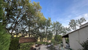 A courtyard with a gravel path, red chairs, a brick wall, and trees. - 3-bedroom house in the Verdon Natural Park (Quinson)