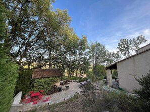 A courtyard with a gravel path, red chairs, a brick wall, and trees. - 3-bedroom house in the Verdon Natural Park (Quinson)