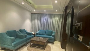 A modern living room with two sofas, a coffee table, and a flat-screen TV mounted on a dark wall. - Gardenia Park Quraish hotel (Jeddah)