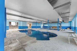 An indoor swimming pool with blue walls and a concrete floor.