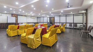 A conference room with yellow chairs and red tablecloths, equipped with ceiling lights and a whiteboard. - Anand Hotel With banquet hall Karol Bagh (New Delhi)