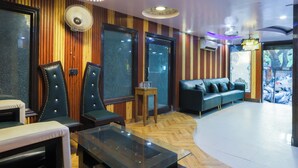 A modern lounge with leather seating, a glass coffee table, and a herringbone wood floor. - Anand Hotel With banquet hall Karol Bagh (New Delhi)