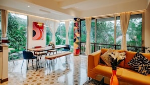 A modern living room with a sofa, coffee table, and dining area. - Palette by RÊVE Escapes - Premium 2 BHK apartment Near Anjuna Beach (Assagao)