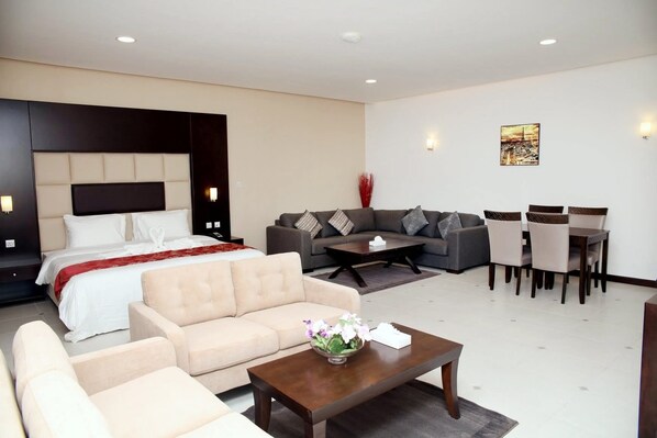 Une chambre d’hôtel moderne avec un grand lit, un canapé, une table à manger avec des chaises et une petite table basse.