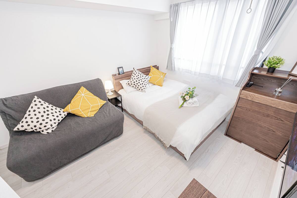 Un dormitorio moderno con una cama, un sofá, una mesita de noche y un aparador.