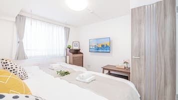 A modern hotel room with a large bed, a bedside table, a small desk, a painting, and a wardrobe.